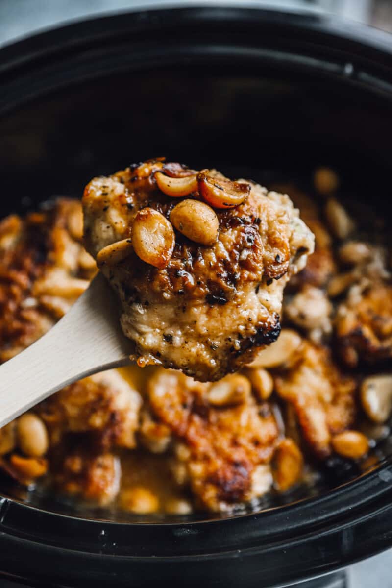 holding garlic chicken above a crockpot