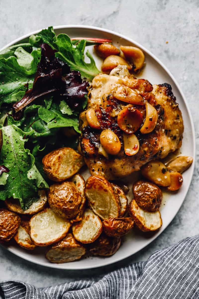 a plate of 40 clove garlic chicken with potatoes and greens