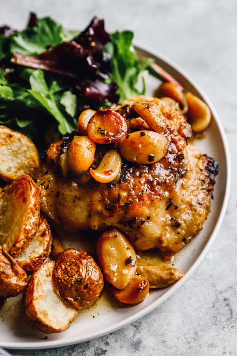 a plate of garlic chicken thighs with potatoes and greens