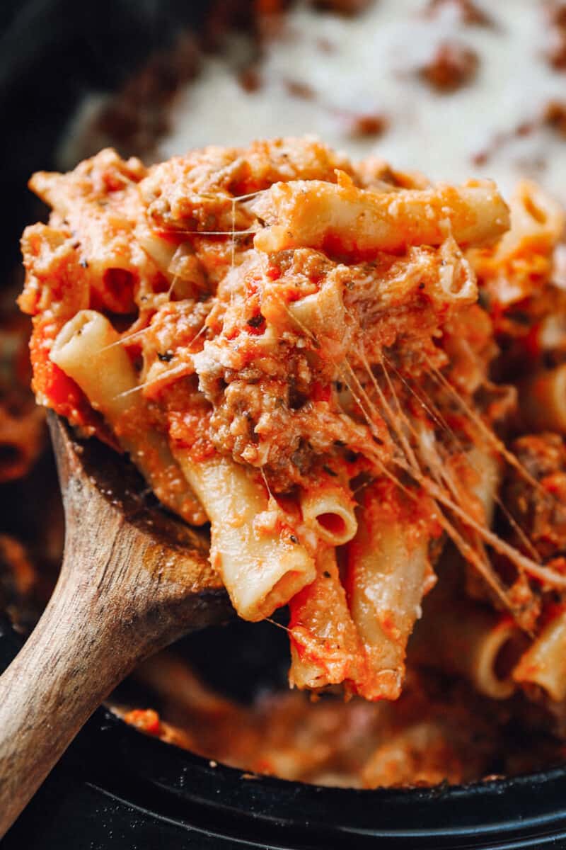 close up of a wooden spoonful of crockpot baked ziti.
