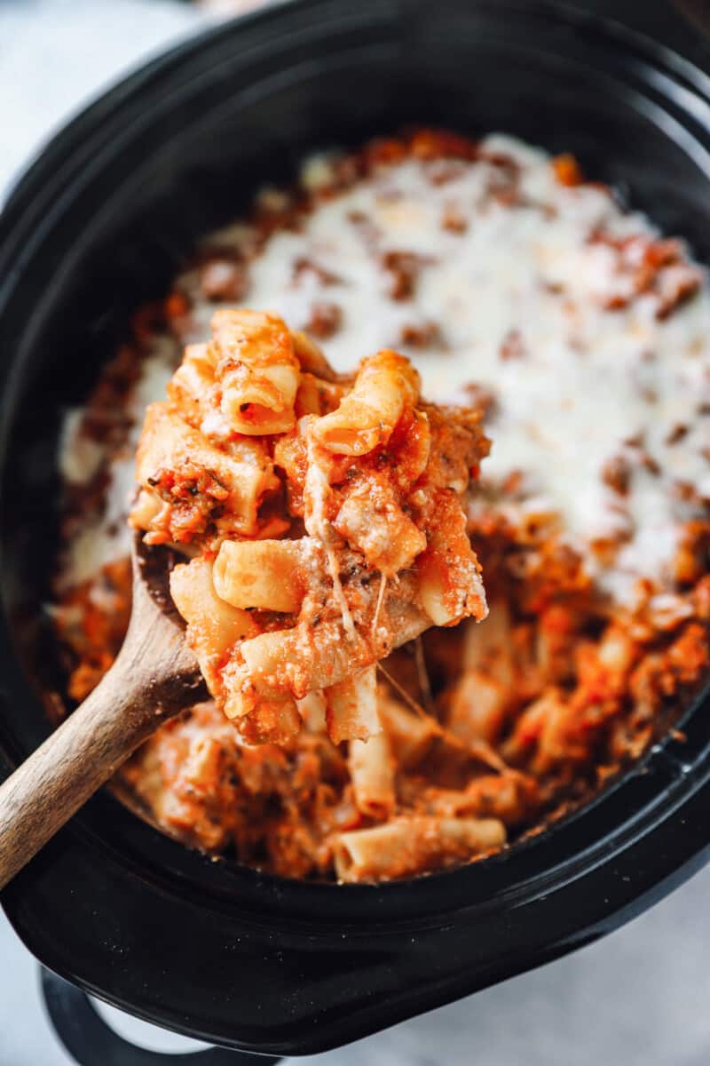 overhead view of a wooden spoonful of crockpot baked ziti.