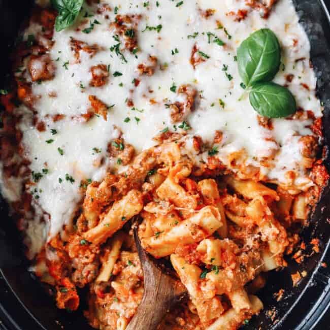 crockpot baked ziti in a crockpot with a wooden spoon.
