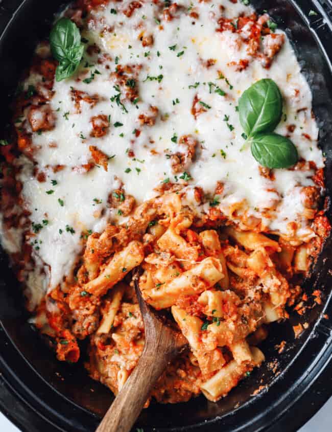 crockpot baked ziti in a crockpot with a wooden spoon.