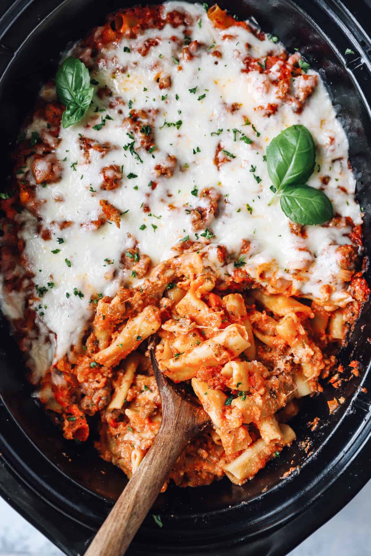 crockpot baked ziti in a crockpot with a wooden spoon.