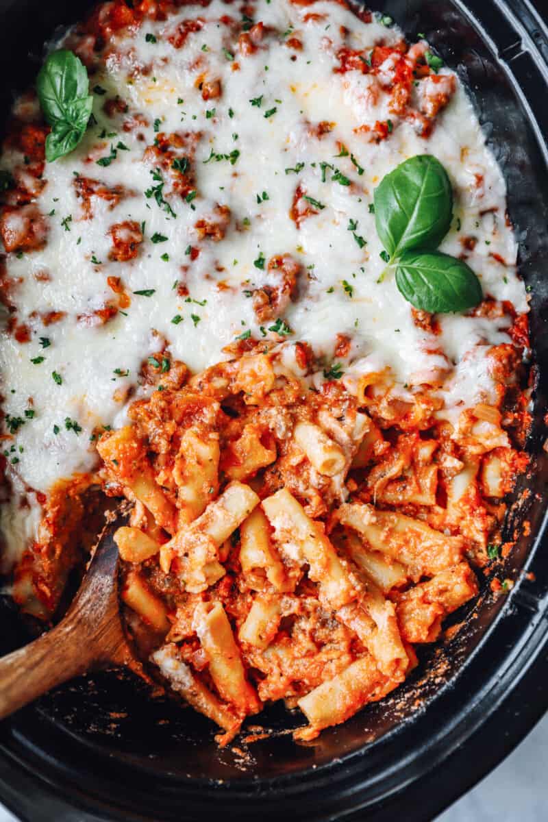 crockpot baked ziti in a crockpot with a wooden spoon.