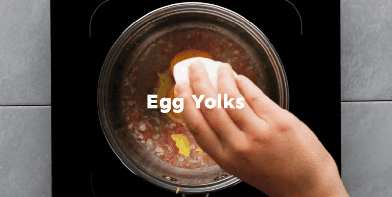 Adding Dijon and egg yolks to the pot.