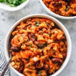 overhead view of crockpot chili mac in white bowls with a fork.