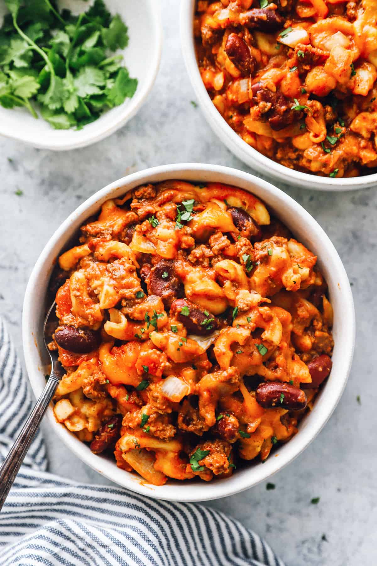 overhead view of crockpot chili mac in white bowls with a fork.