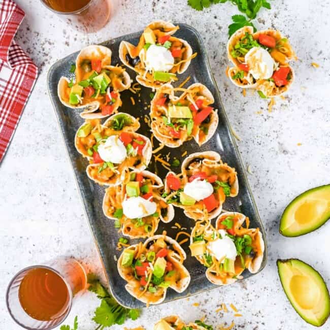 overhead view of 8 enchilada cups on a metal serving tray.