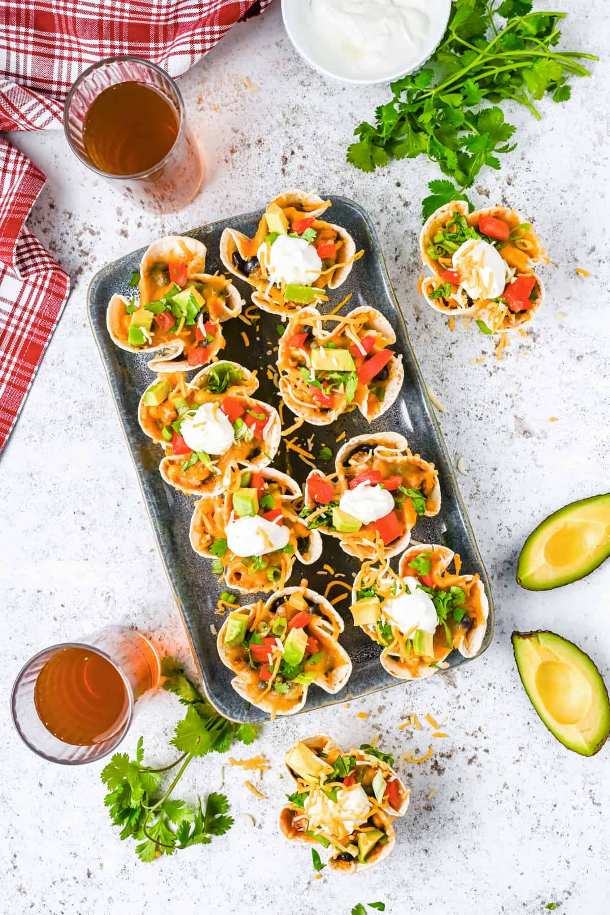 overhead view of 8 enchilada cups on a metal serving tray and 2 on a counter.