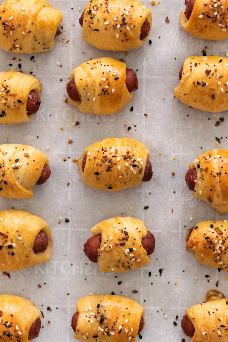 everything bagel pigs in a blanket lined up on parchment paper