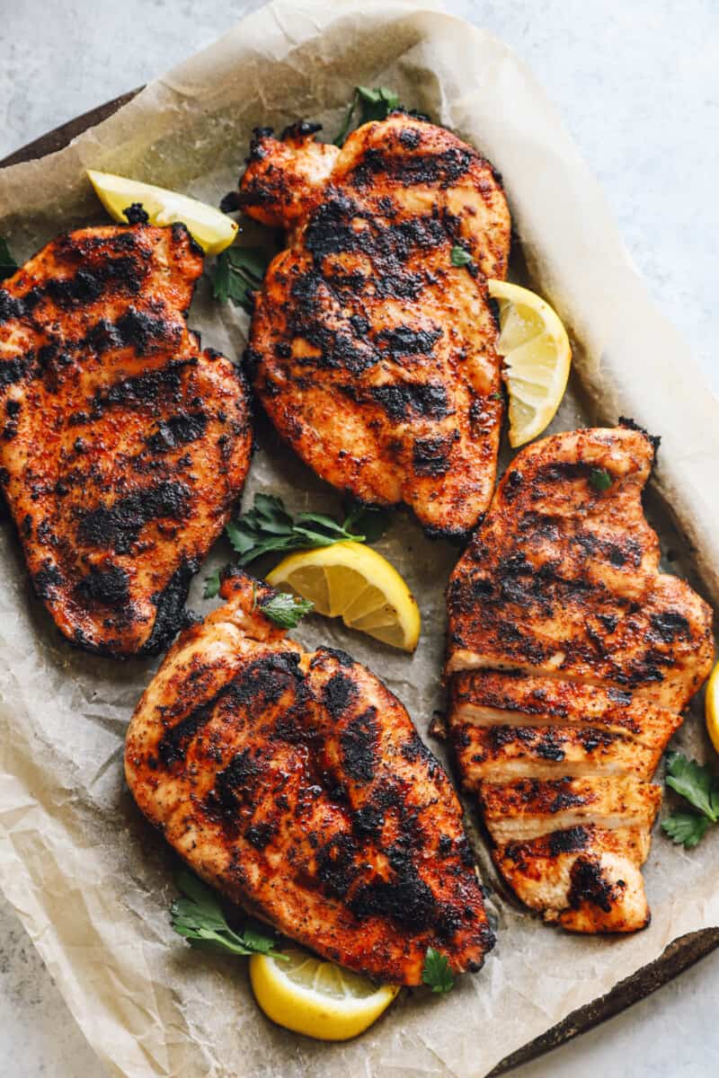 four grilled chicken breasts on a baking tray
