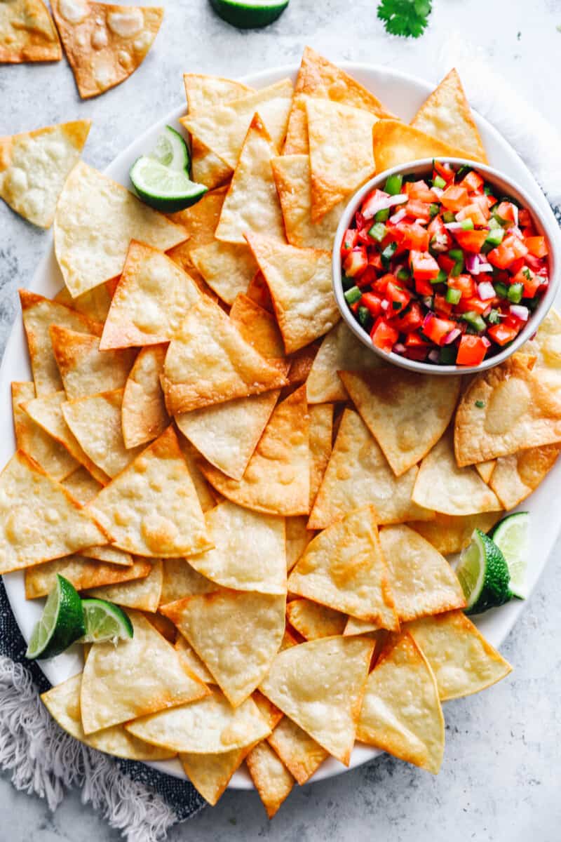 overhead view of tortilla chips on a white tray with salsa.