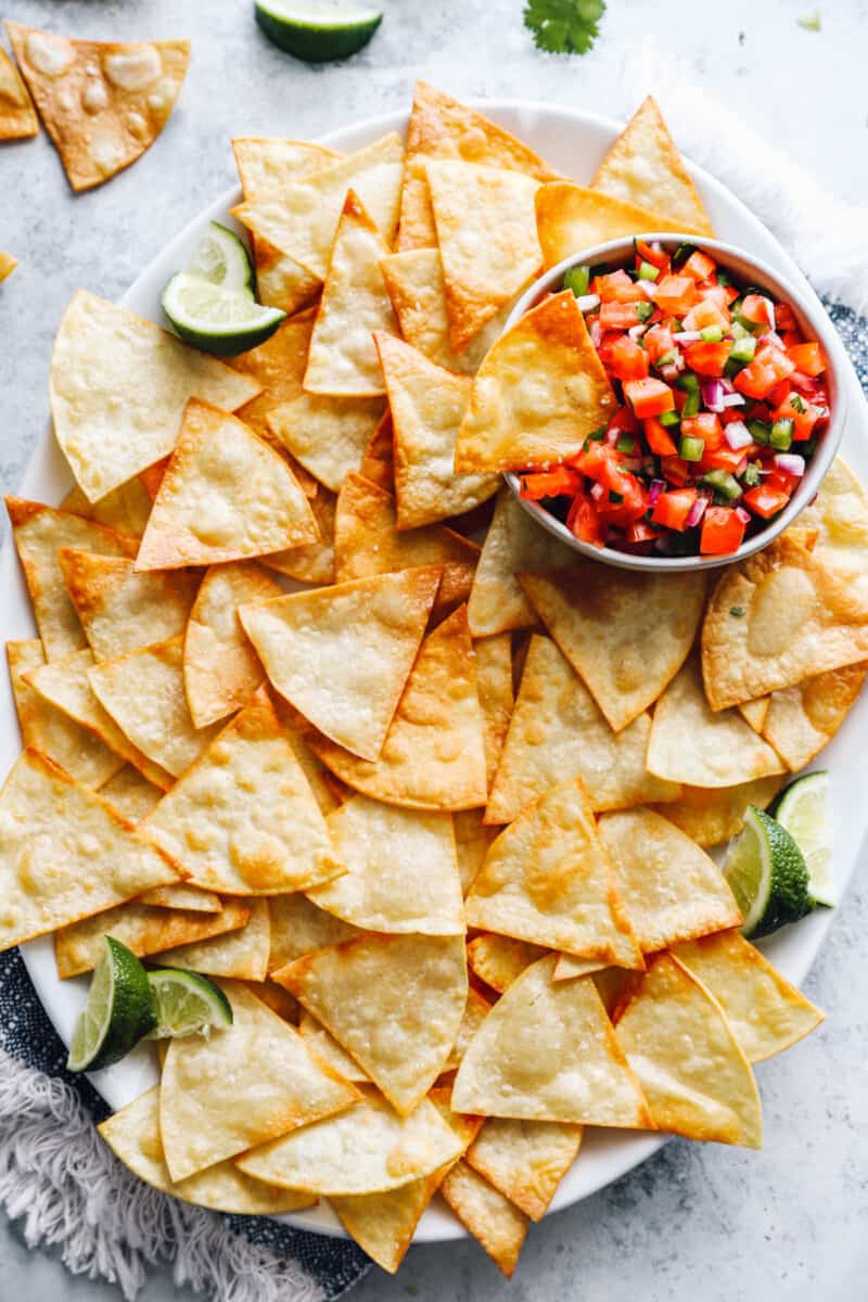 overhead view of homemade tortilla chips on a white tray with salsa.