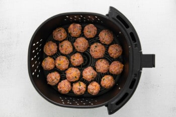 raw air fryer sausage balls in the basket of an air fryer.