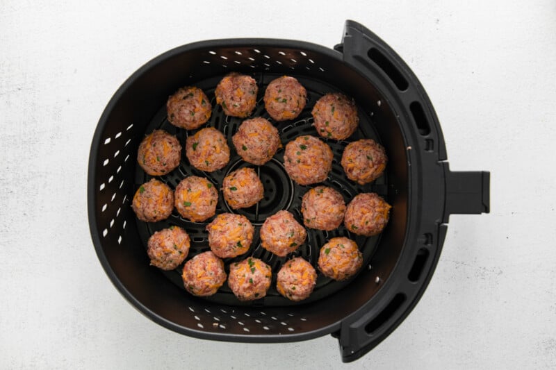 raw air fryer sausage balls in the basket of an air fryer.