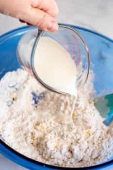pouring milk into a bowl of dry ingredients