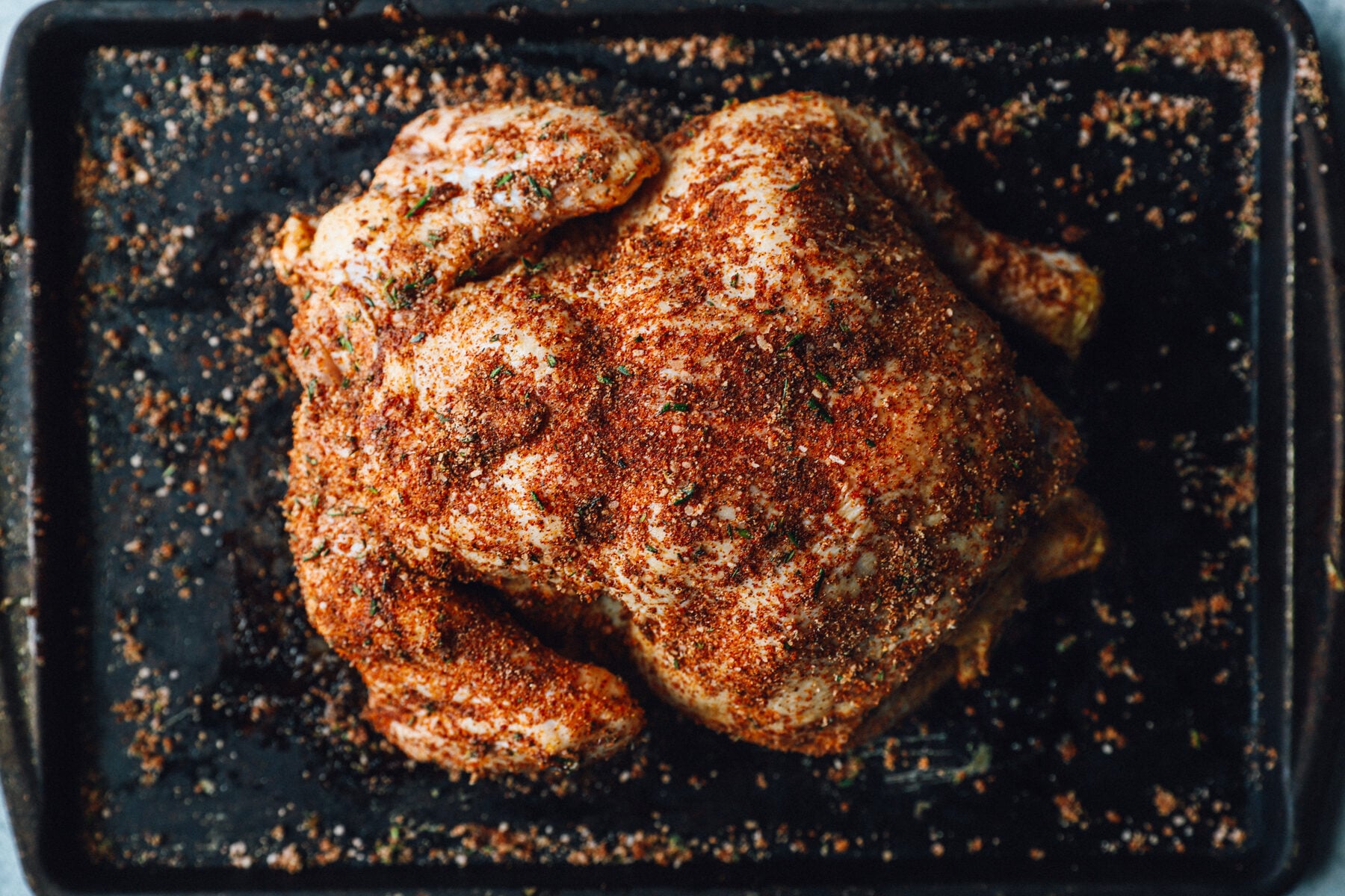 a whole chicken, seasoned, on a baking pan