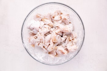 cornstarch coated chicken pieces in a glass bowl.