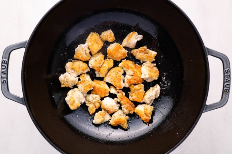 cooked chicken pieces in a cast iron wok.