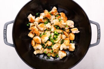 cooked chicken and green onions in a cast iron wok.