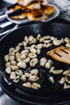 sautéing garlic cloves in a skillet