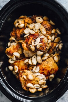 chicken thighs and garlic cloves in a slow cooker