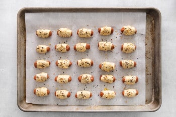 unbaked pigs in a blanket lined up on a baking tray