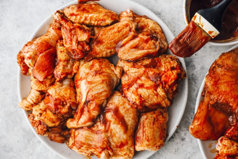 brushing grilled chicken with BBQ sauce