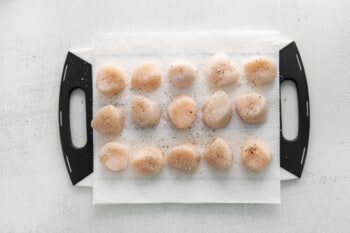 uncooked scallops lined up on a cutting board
