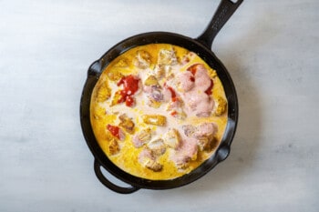 butter chicken sauce ingredients added to a cast iron skillet.