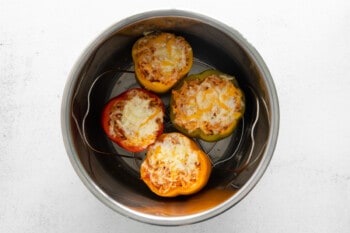cheese sprinkled over instant pot stuffed peppers in an instant pot.