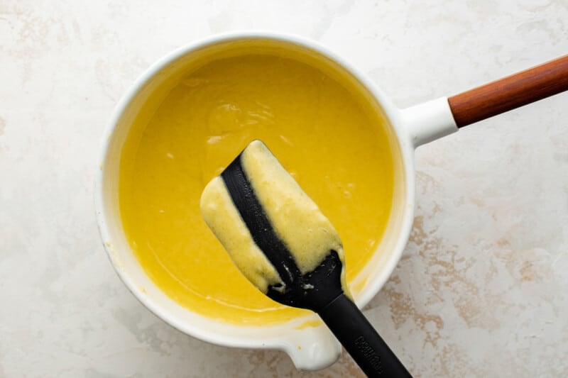 rubber spatula being held over a pot of lemon curd