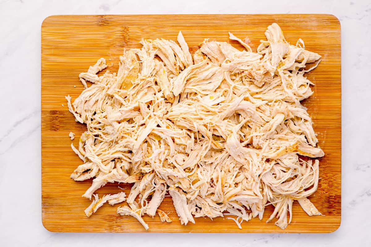 Shredded chicken breasts on a cutting board. - 8