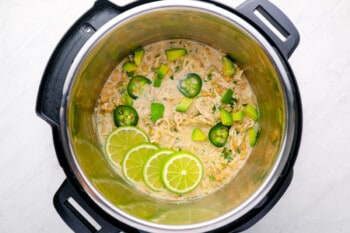 instant pot white chicken chili in an instant pot garnished with jalapeños and lime slices.