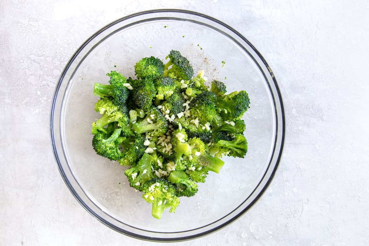 Seasoned broccoli in a glass bowl.