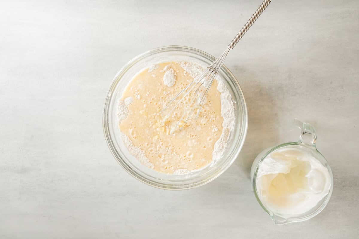 partially mixed belgian waffle batter in a glass bowl with a whisk.