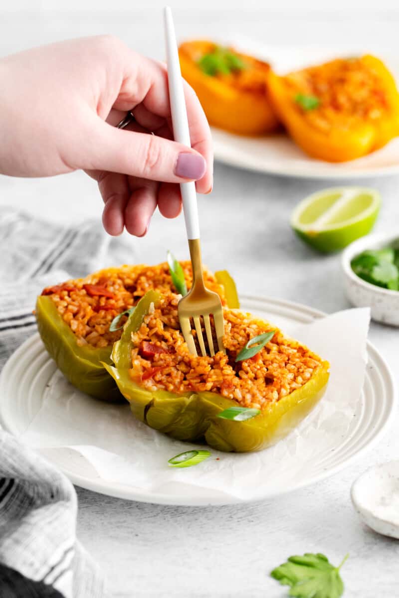 a fork scooping filling from an instant pot stuffed pepper on a white plate.