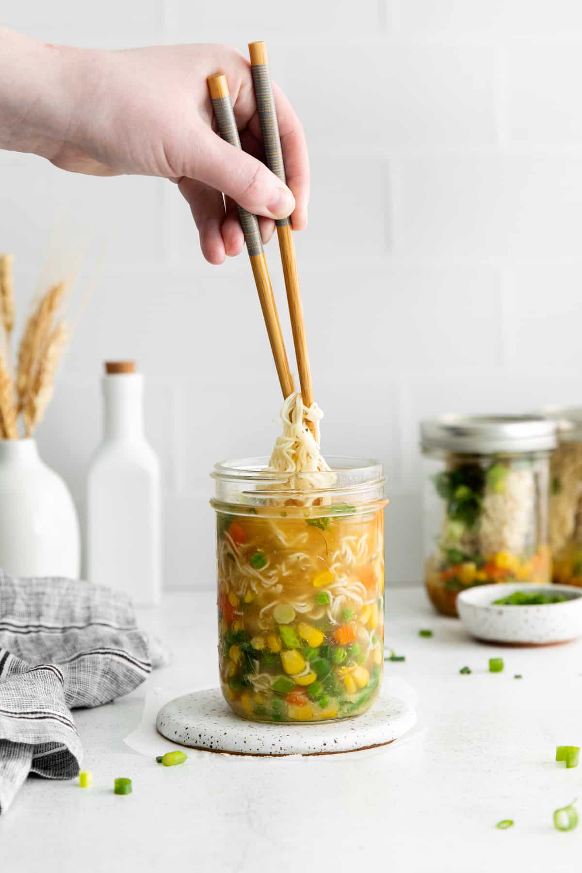 hand picking up noodles with chopsticks out of a jar of homemade ramen