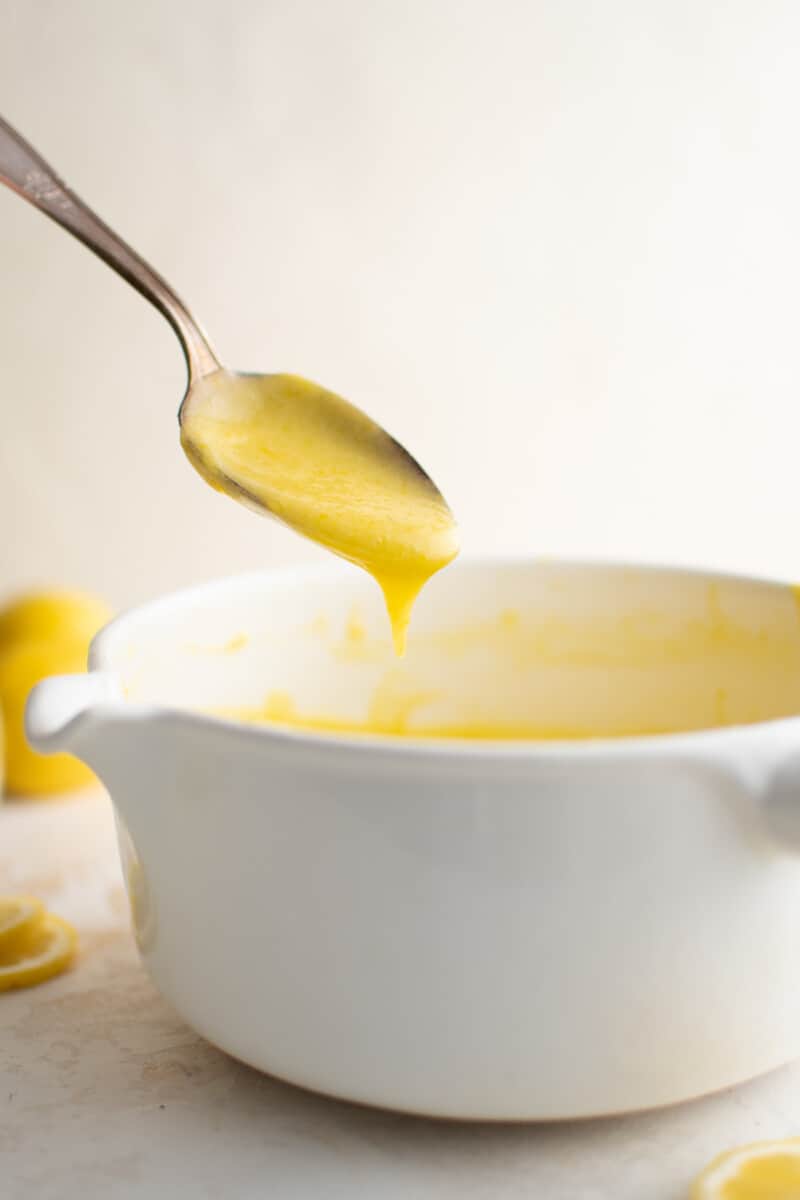 dipping a spoon into a pot of lemon curd