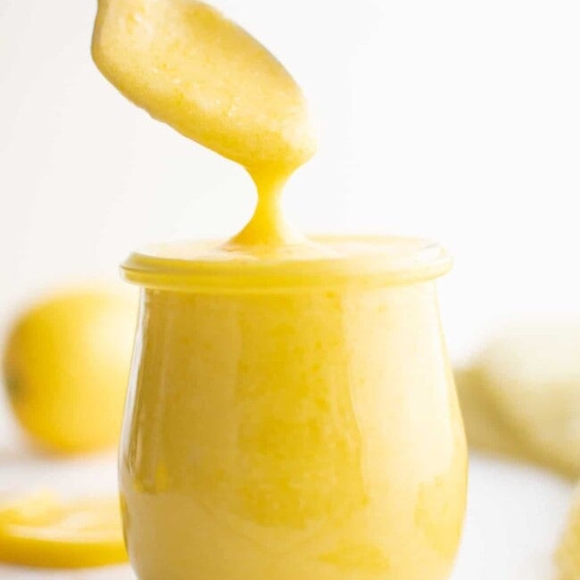 a spoon dipping into a jar of lemon curd