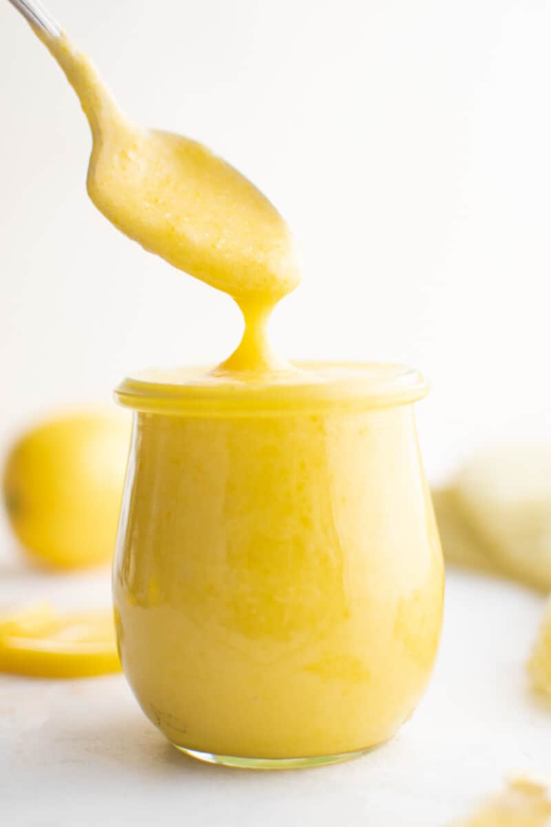 a spoon dipping into a jar of lemon curd