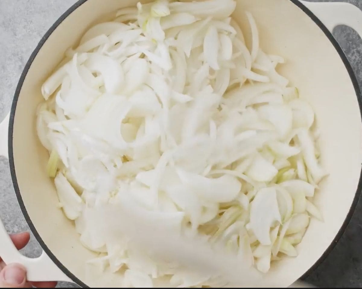 Sliced yellow and sweet onions in a Dutch oven before cooking