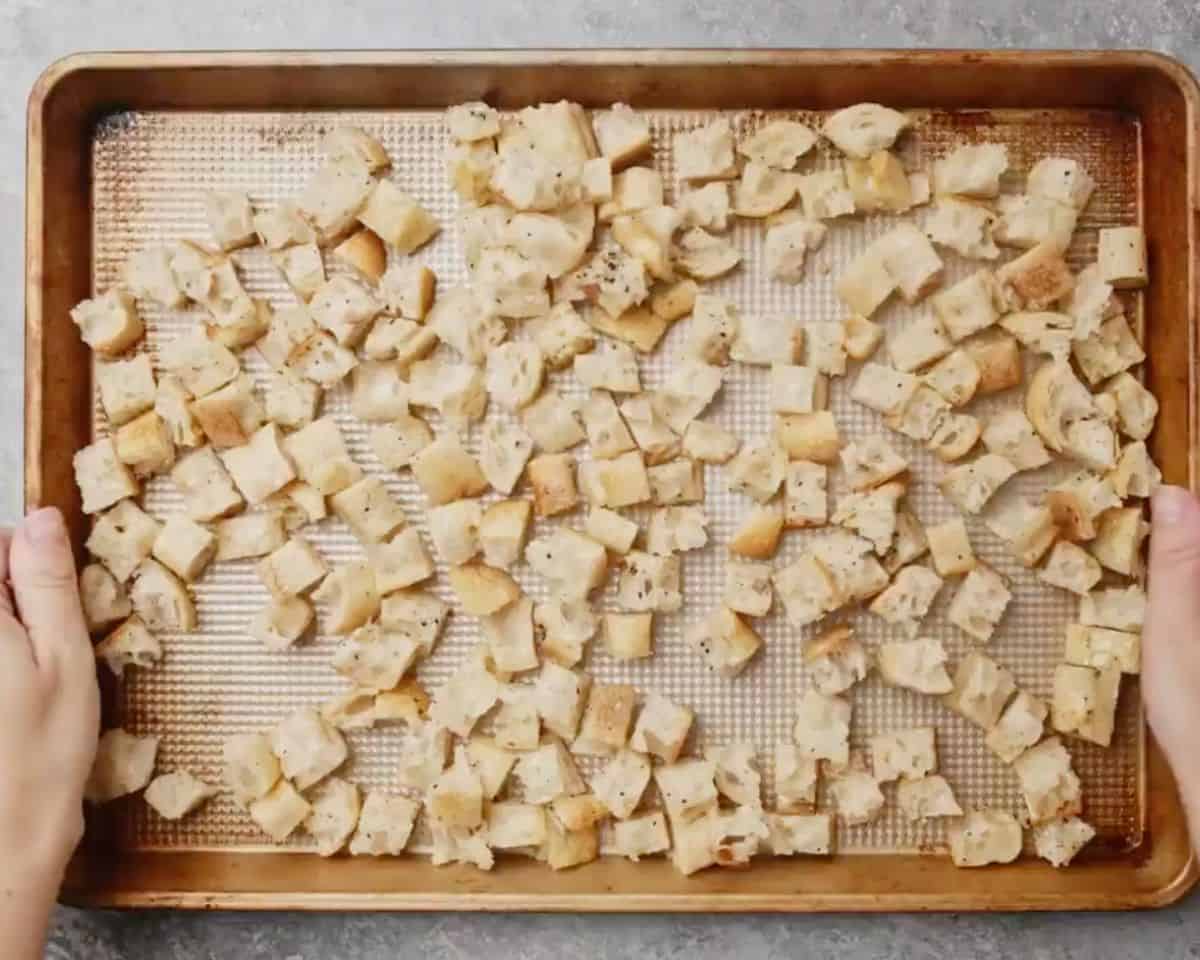 Homemade croutons spread on a baking sheet before baking