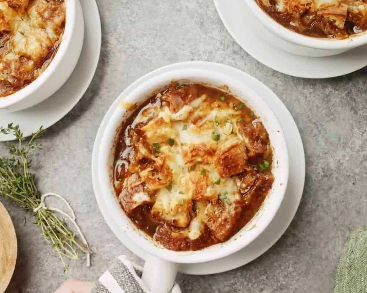 French onion soup in a ramekin topped with melted Gruyère cheese and toasted croutons