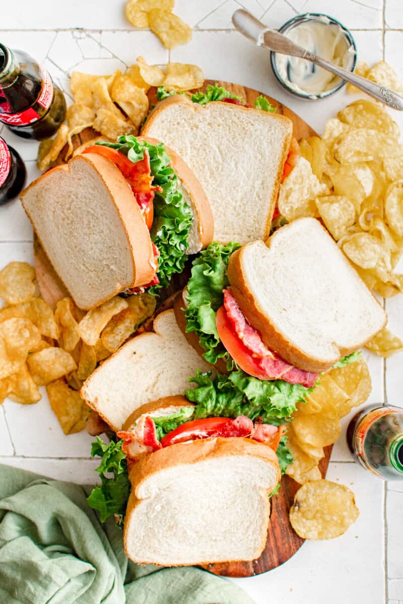 overhead view of 5 blt sandwiches resting on a bed of potato chips.