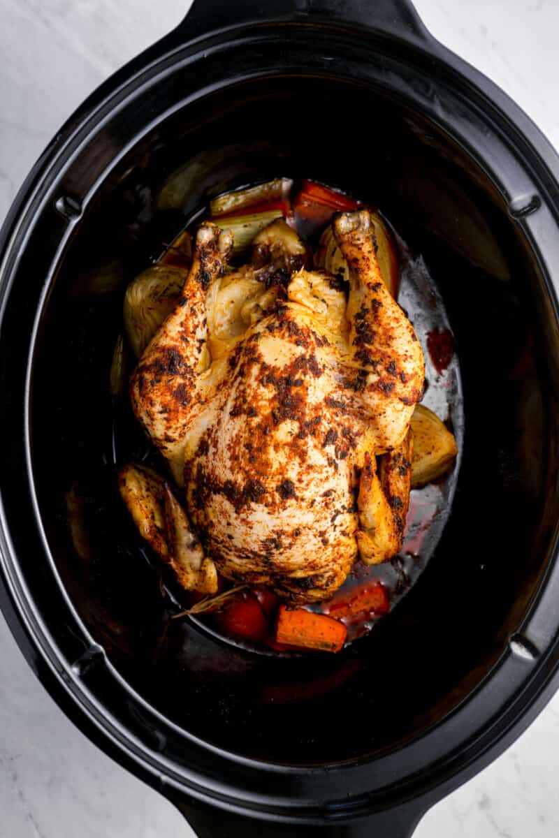 whole chicken in a crockpot with vegetables.