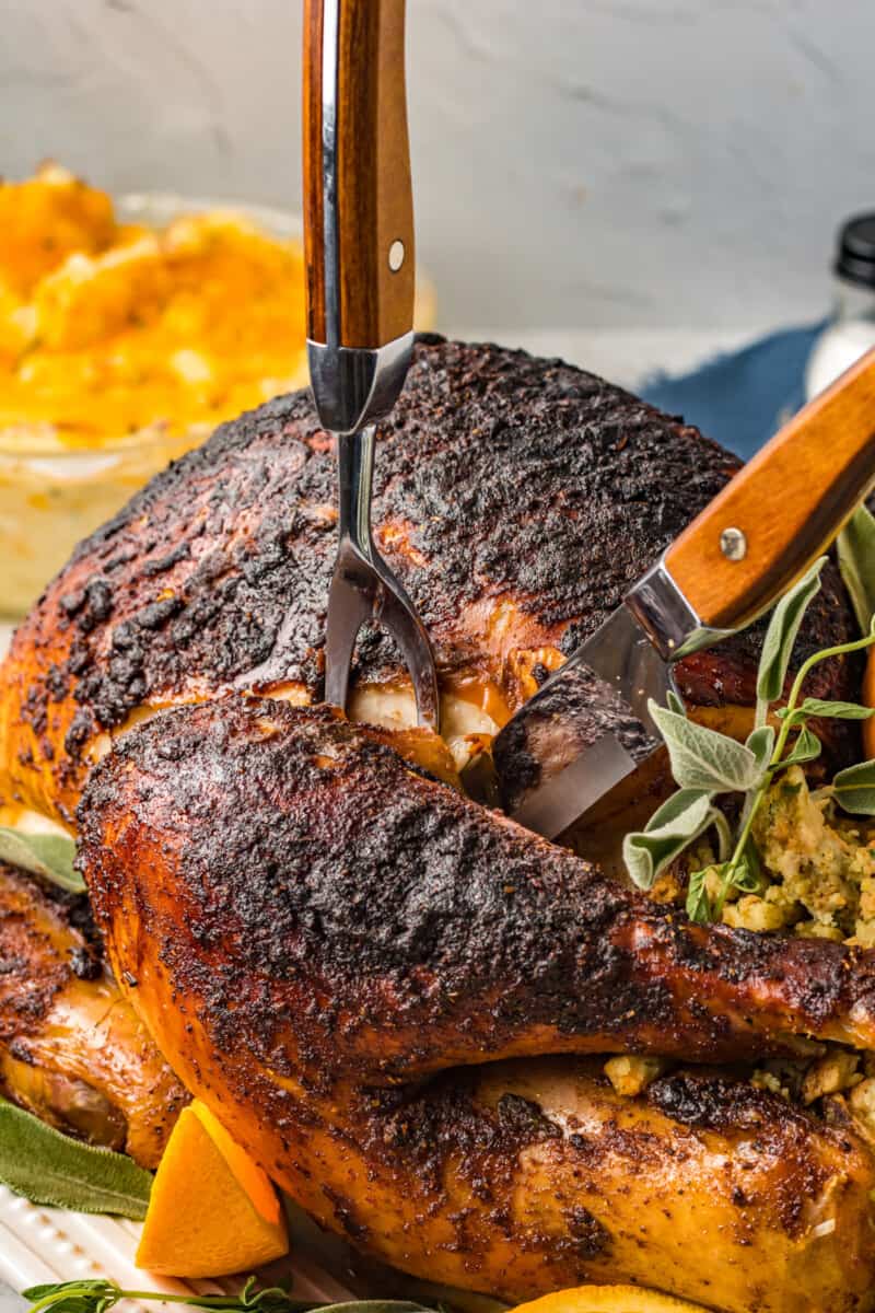 a sliced rubbed turkey with stuffing, sage leaves, and oranges.