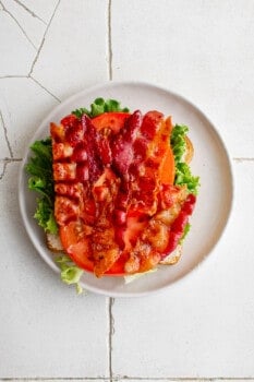 bacon stacked on top of tomatoes, lettuce, and mayonnaise on a slice of bread.