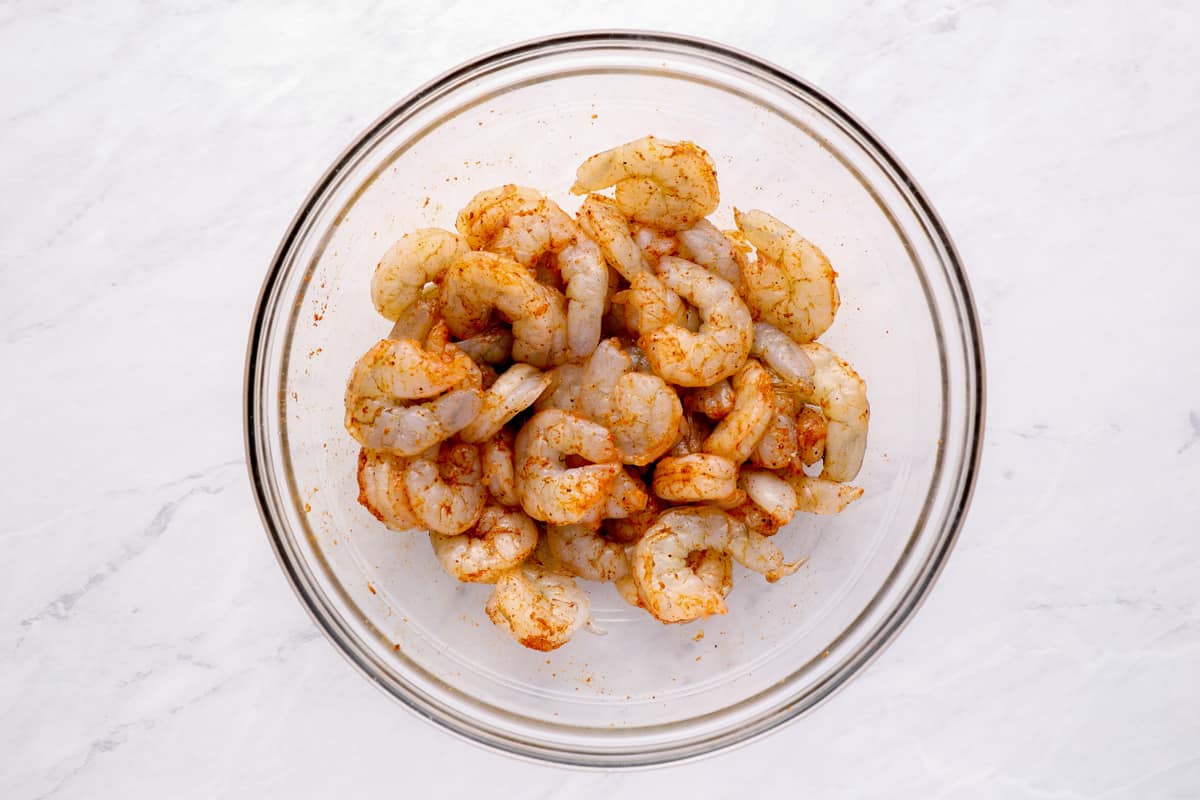 A bowl of raw shrimp coated in Cajun seasoning.